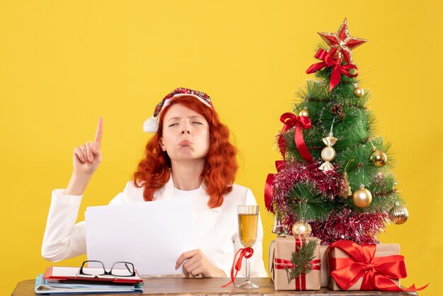 Free photo front view female doctor holding documents behind table with presents sad