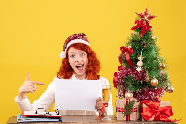 Front view female doctor holding documents behind table with presents