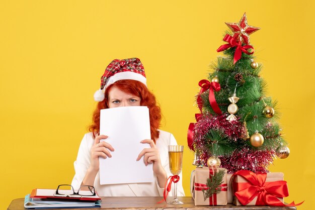 Front view female doctor holding documents behind table with presents