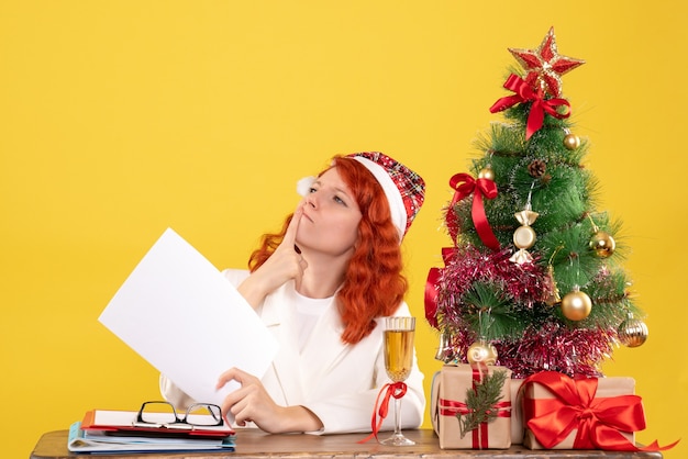 Front view female doctor holding documents behind table with presents