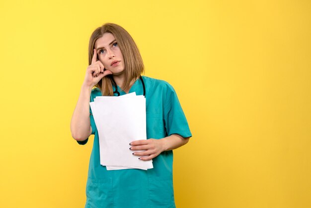 Front view female doctor holding documents on a yellow space