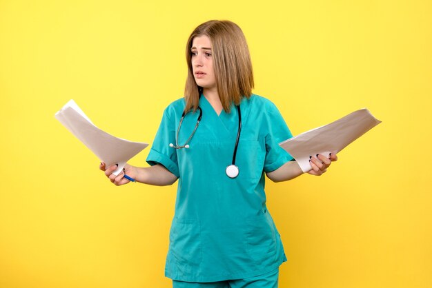 Front view female doctor holding documents on the yellow space