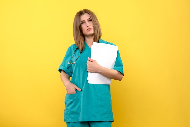 Front view female doctor holding documents on the yellow space