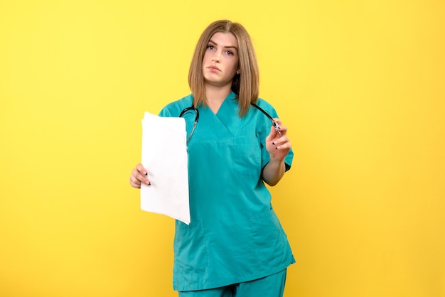 노란색 공간에 문서를 들고 전면보기 여성 의사