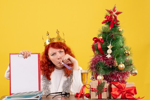 Front view female doctor holding file note around xmas tree and presents