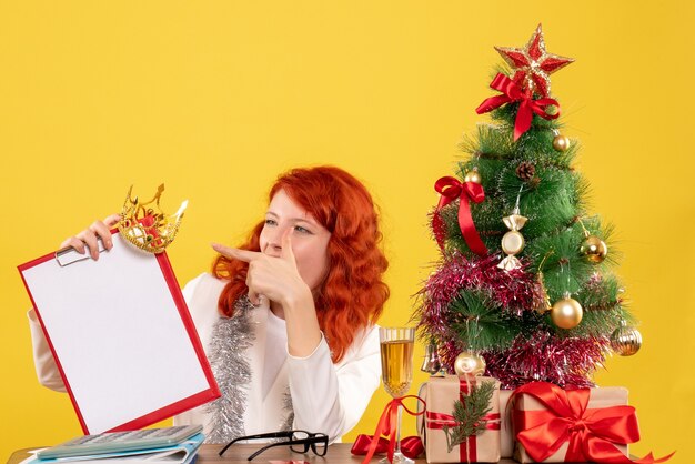 クリスマスツリーとプレゼントの周りにファイルメモを保持している正面図の女性医師