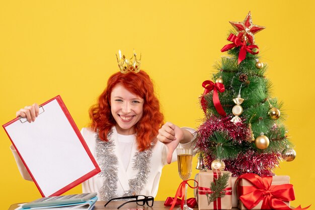 Front view female doctor holding file note around xmas tree and presents