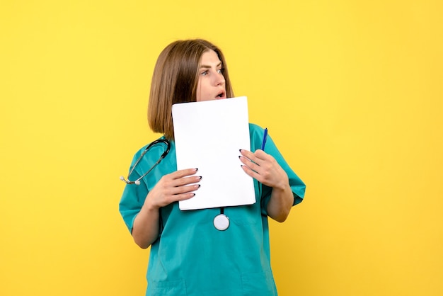 黄色い床の医療病院の色でファイルを保持している正面図の女性医師