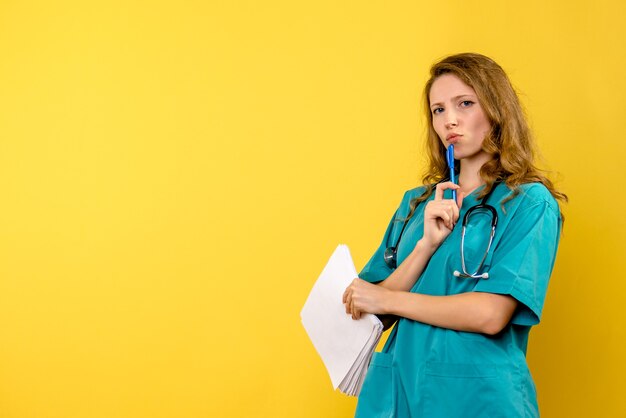Front view female doctor holding files on a yellow space