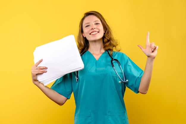 Front view female doctor holding files on a yellow space