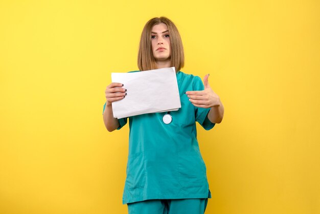 Front view female doctor holding files on a yellow space