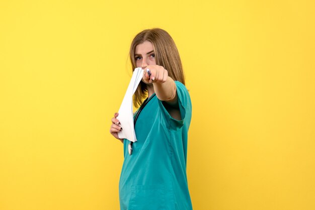 Front view female doctor holding files on a yellow space