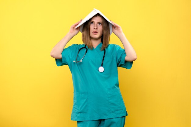 Front view female doctor holding files on the yellow space