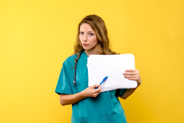 Вид спереди женщина-врач, держащая файлы на желтом пространстве