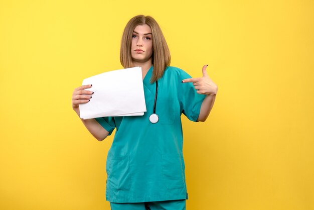 Вид спереди женщина-врач, держащая файлы на желтом пространстве