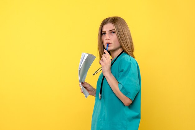 Front view female doctor holding files on yellow space