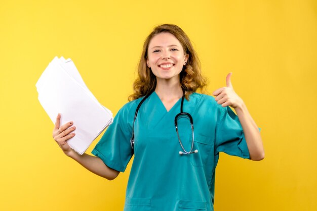 Front view female doctor holding files on yellow space