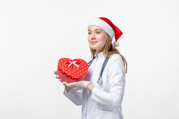 白い壁に休日のプレゼントを保持している女性医師の正面図