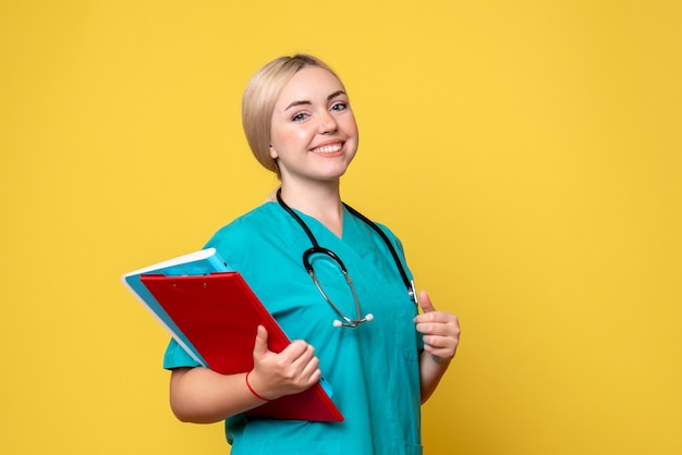 Front view female doctor holding notes and analysis, medic ambulance hospital health covid-19 nurse