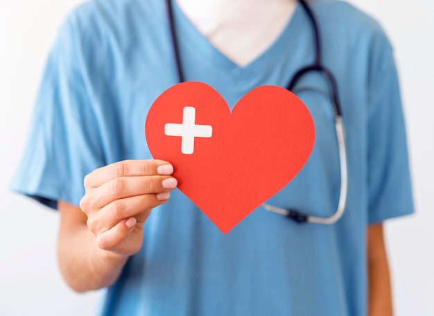 Front view of female doctor holding paper heart