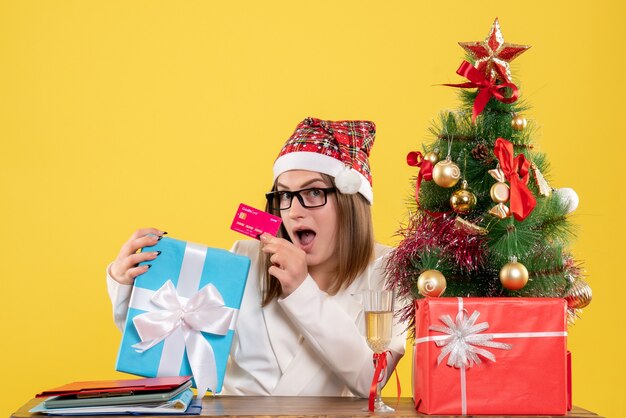 Front view female doctor holding present and bank card