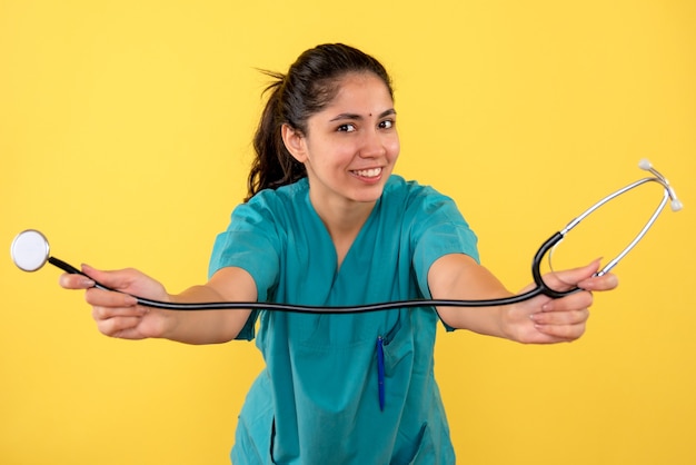 Front view female doctor holding stethoscope in both hands standing