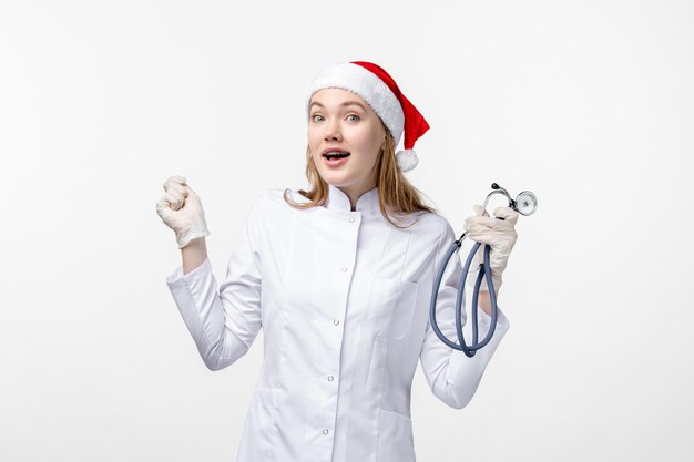 Front view of female doctor holding stethoscope on the white wall