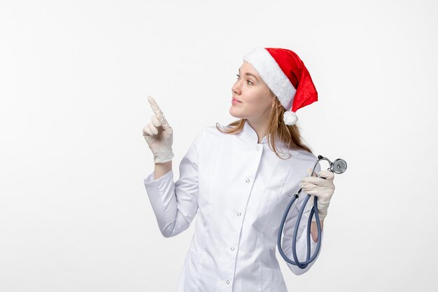 Front view of female doctor holding stethoscope on the white wall