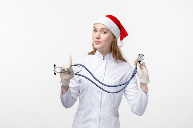 Front view of female doctor holding stethoscope on white wall