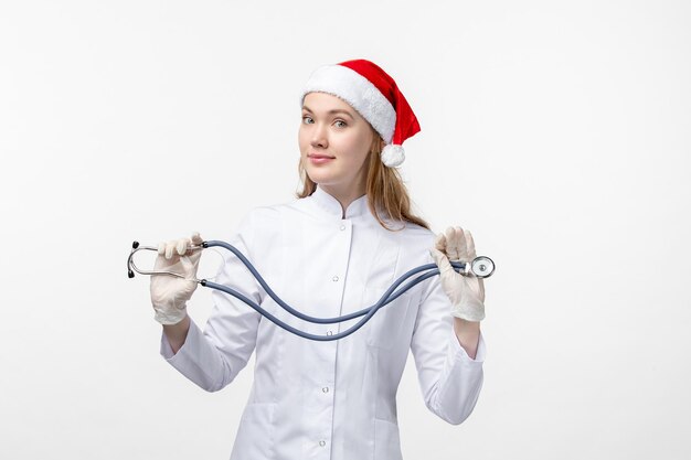 Front view of female doctor holding stethoscope on white wall