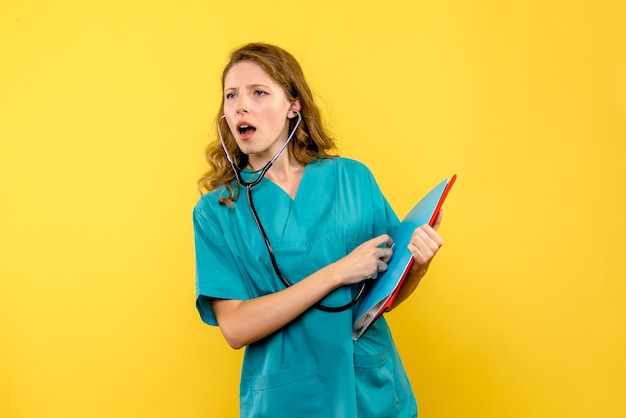 Free photo front view female doctor holding stethoscope on a yellow space