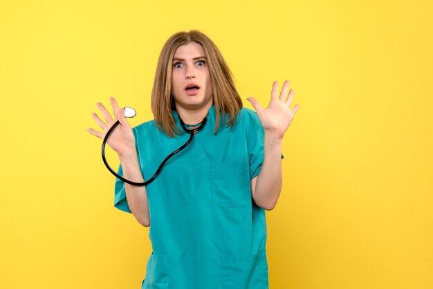Вид спереди женщина-врач держит тонометр на желтом полу больницы медицинские эмоции