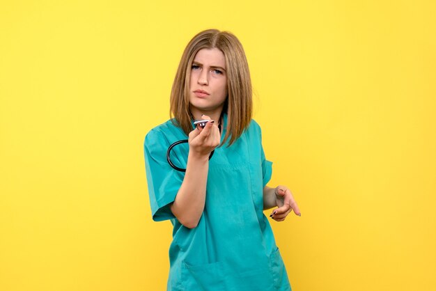 Front view female doctor holding tonometer on a yellow space