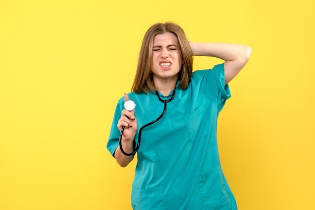 Front view female doctor holding tonometer on yellow space