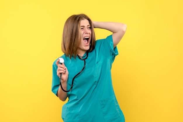 Front view female doctor holding tonometer on yellow space