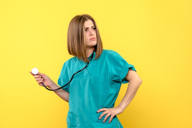 Front view female doctor holding tonometer on yellow space