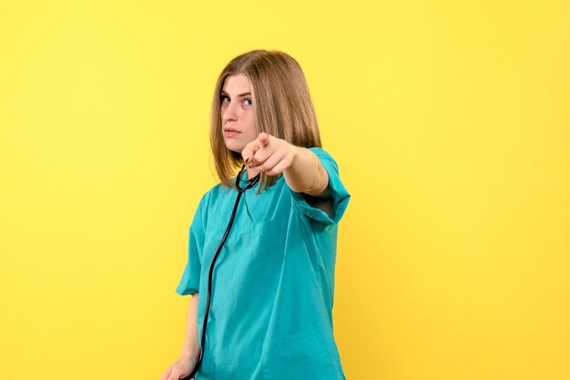 Front view female doctor holding tonometer on yellow space