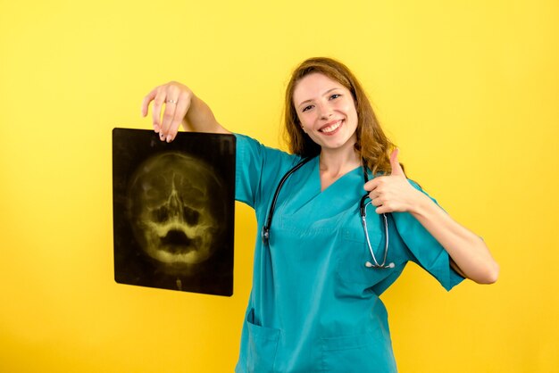 Вид спереди женщина-врач, держащая рентген на желтом пространстве