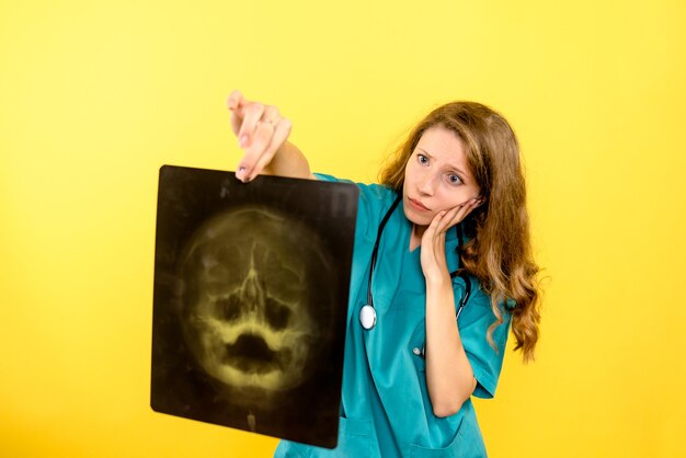 Front view female doctor holding x-ray on yellow space