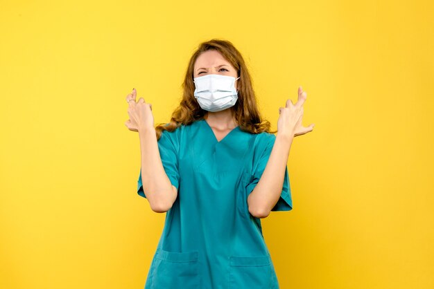 Free photo front view female doctor hoping in mask on yellow space