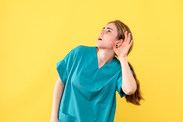 Front view female doctor imitating listening on yellow background medic hospital health emotion