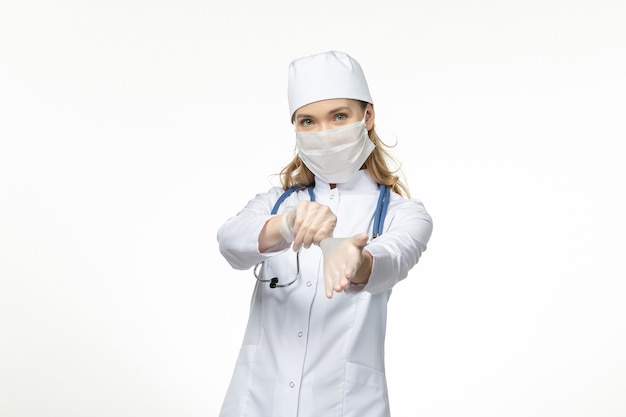 흰 벽 질병 유행성 코로나 바이러스에 코로나 바이러스로 인해 장갑과 마스크를 쓰고 의료 소송에서 전면보기 여성 의사