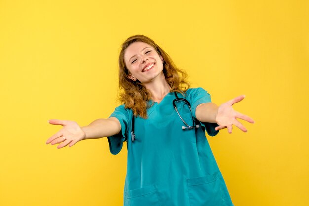 Front view of female doctor just smiling on yellow wall