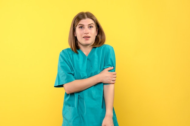 Вид спереди женщина-врач просто стоя на желтом пространстве
