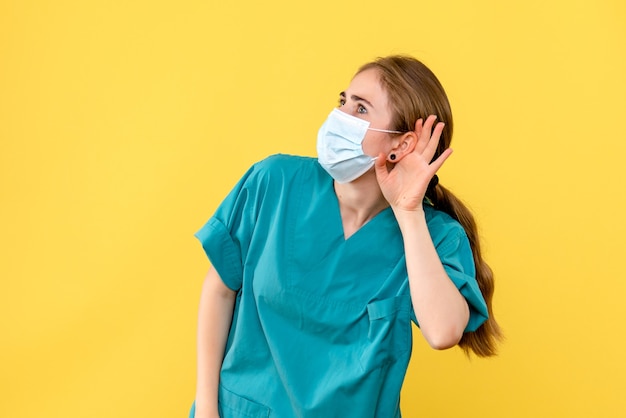 Front view female doctor listening on yellow background health hospital covid- pandemic