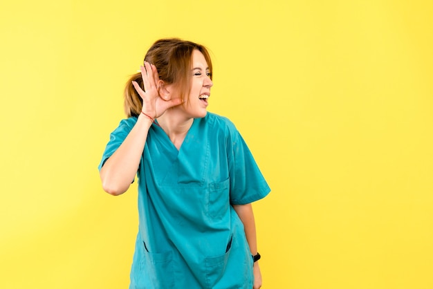 Front view female doctor listening on yellow space