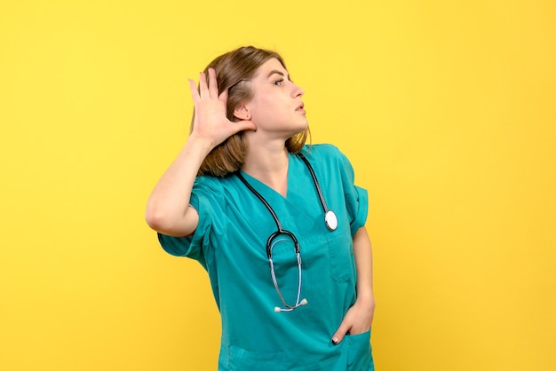 Front view female doctor listening on yellow space