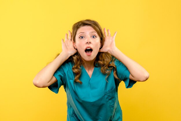 Front view female doctor listening on yellow space