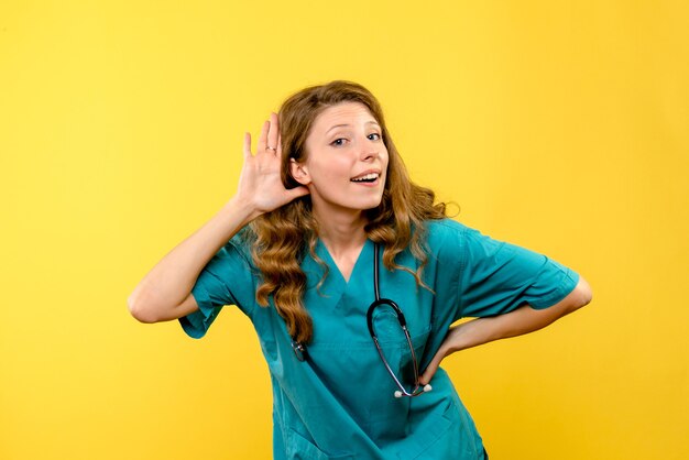 Front view of female doctor listening on yellow wall
