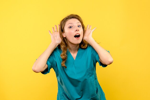 Front view of female doctor listening on yellow wall